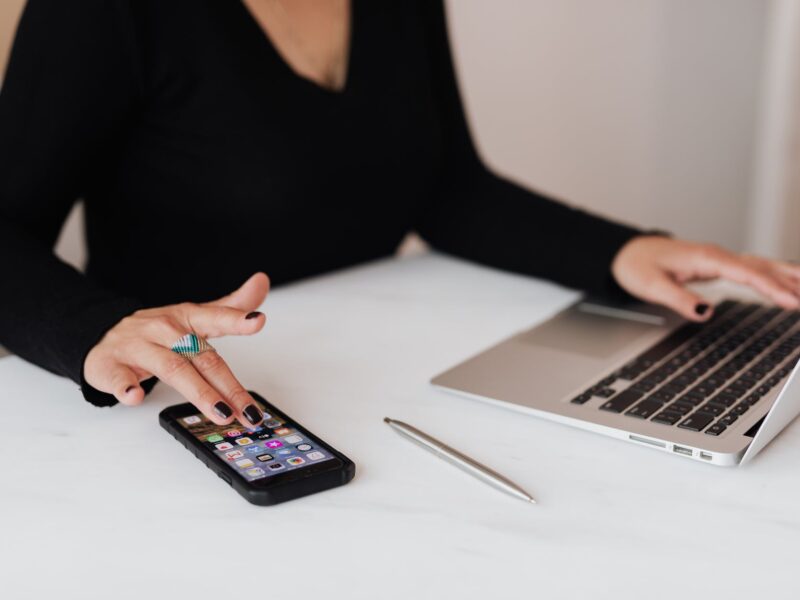 crop woman using smartphone and laptop during work in office