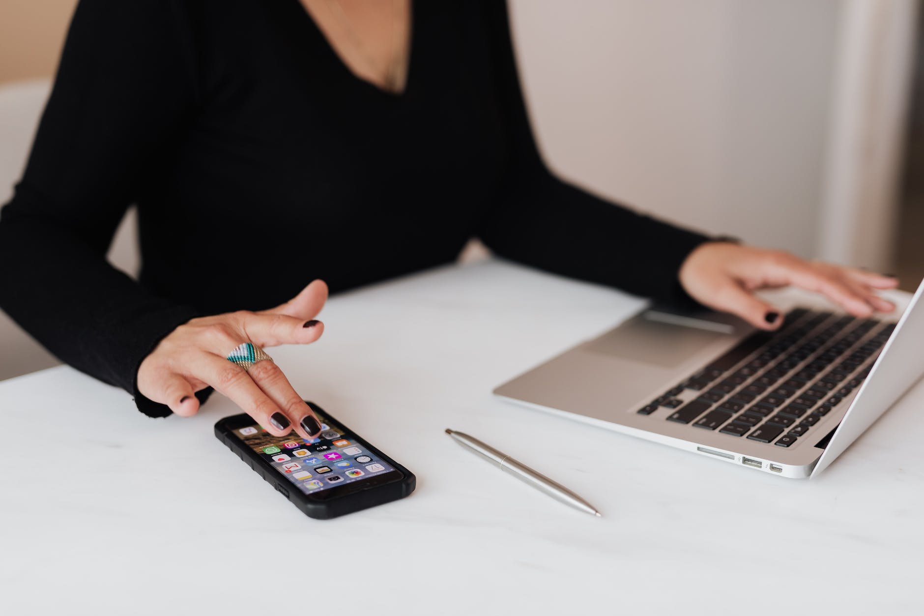 crop woman using smartphone and laptop during work in office