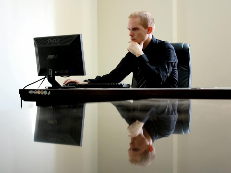 man sitting facing pc inside room